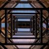 A view looking up at the underside of a building with a large bell in the center.